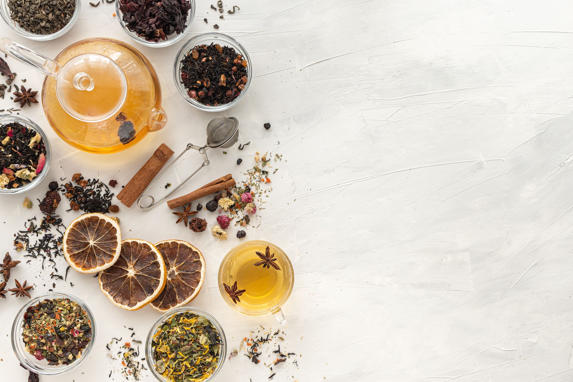 A set of different varieties of Chinese herbal and green tea in a glass dish and a kettle with hot tea on a green background. View from above. Space for text. Herbal treatment. Healthy lifestyle.